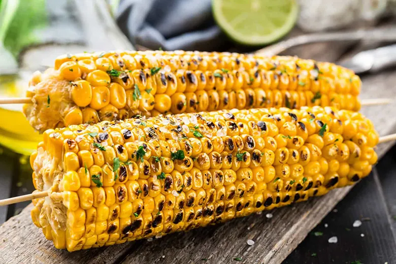 Bắp ngô nướng chín vàng đều, phết bơ và rắc muối tiêu