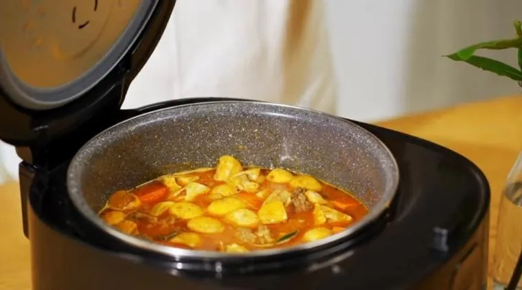 Thịt bò đang hầm trong nồi cơm điện với nước sốt sôi nhẹ