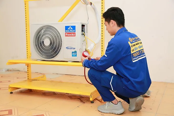 Kỹ thuật viên đang nạp gas máy lạnh với đồng hồ manifold và bình gas chuyên dụng
