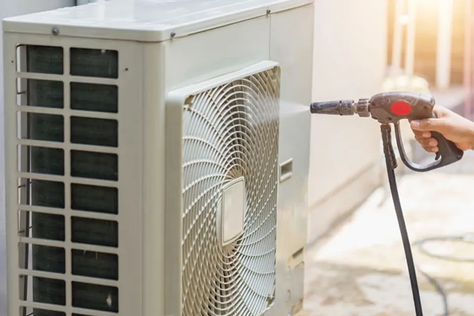 Cục nóng máy lạnh đang được làm sạch lớp bụi dày bằng máy bơm áp lực cao